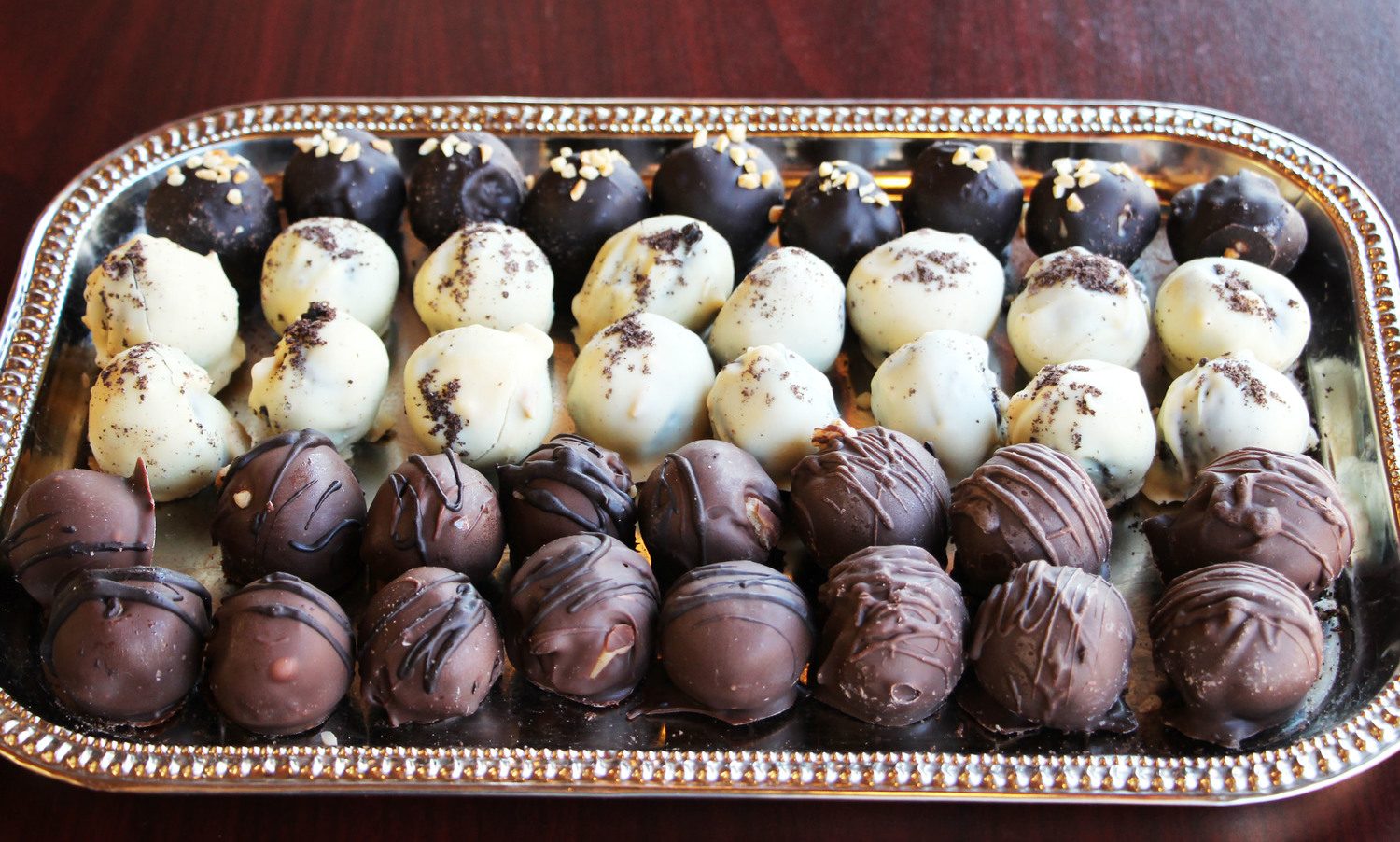 Dark, white and milk chocolate bon bons on a silver tray