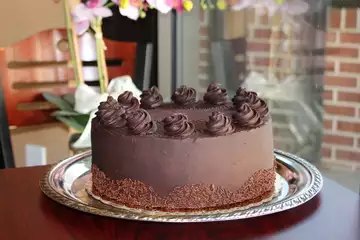 Chocolate mousse cake with piped chocolate rosettes and a sprinkled base