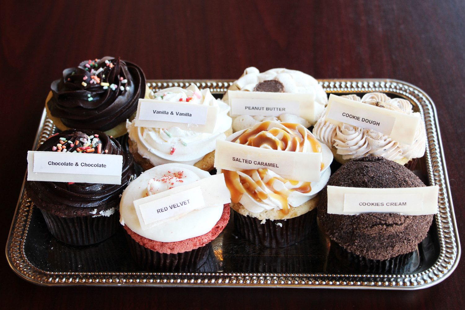 Large cupcakes labelled chocolate, vanilla, peanut butter, cookie dough, red velvet, salted caramel and cookies and cream