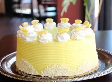 Lemon dream cake in pale yellow with cream rosettes and candied lemon
