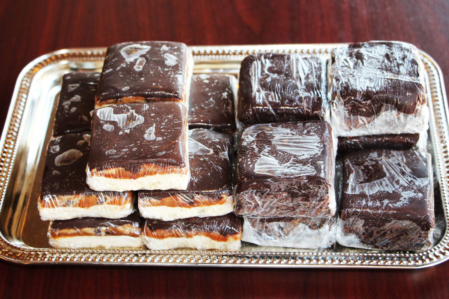 Wrapped millionaire bars and fudge brownie bars on a tray
