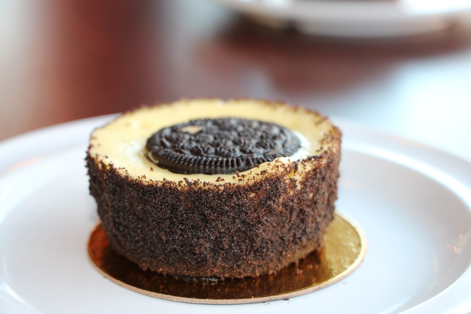 Oreo cheesecake crusted in cookie crumb with a whole Oreo on top