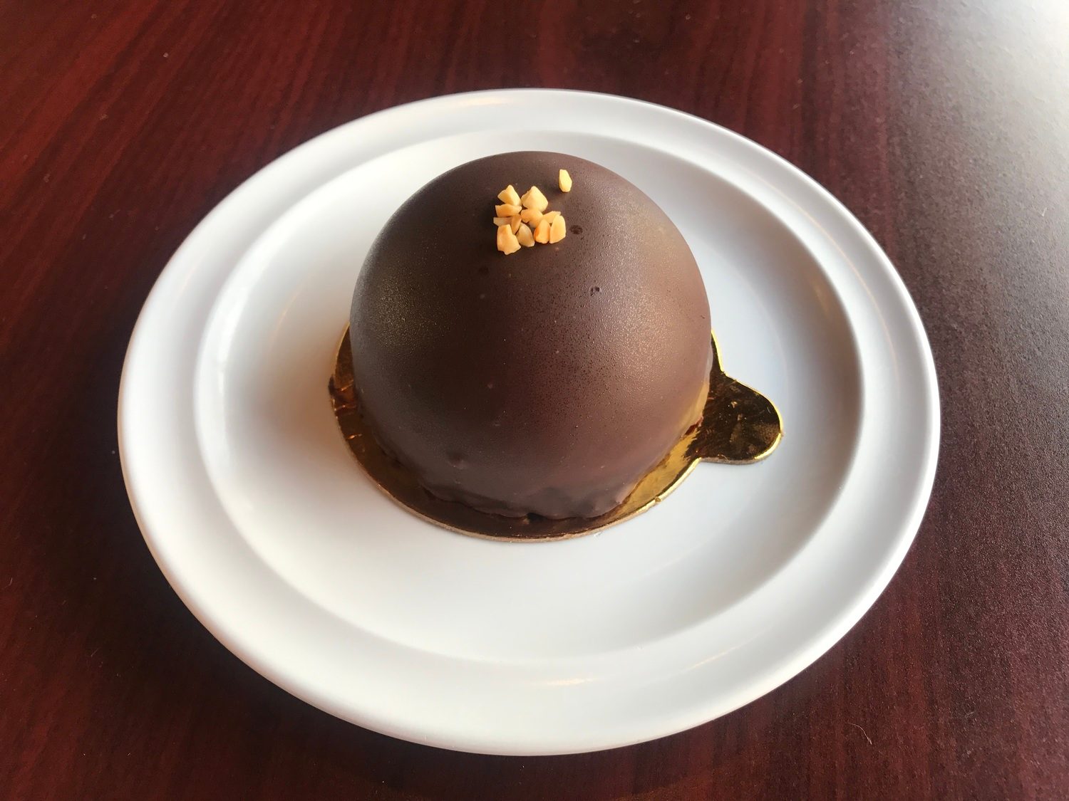 Peanut butter mousse dome under a dark chocolate glaze, topped with chopped peanuts