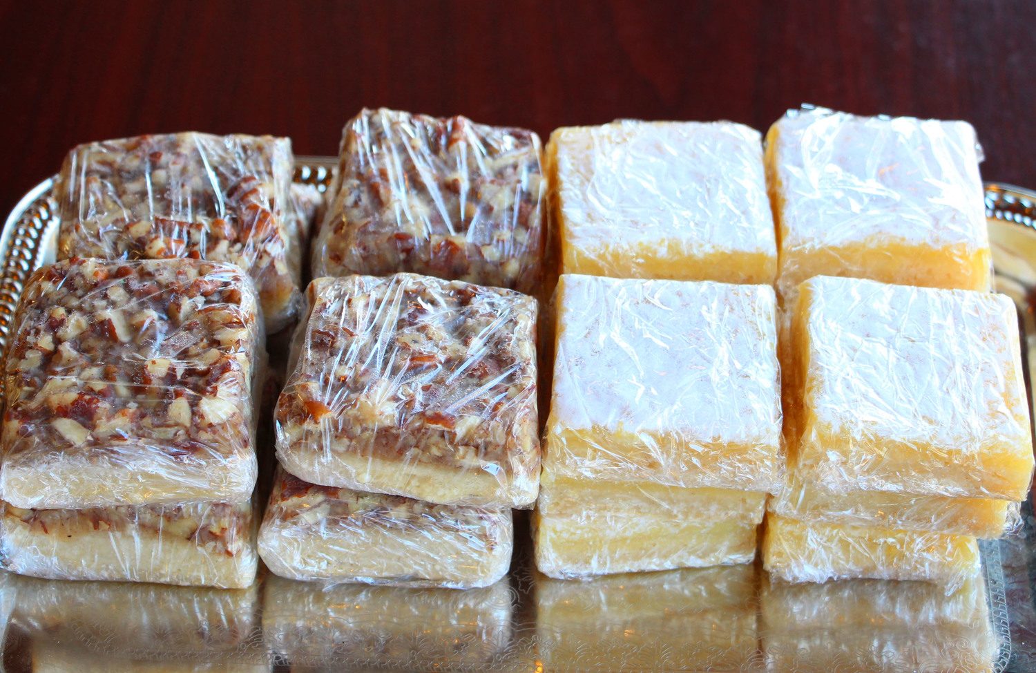 Wrapped caramel butter pecan bars beside powdered lemon bars