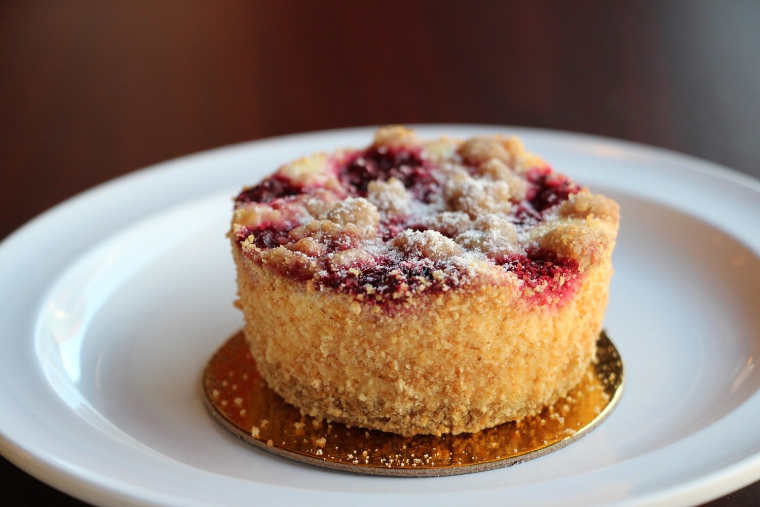 Raspberry crumble cheesecake under streusel and powdered sugar