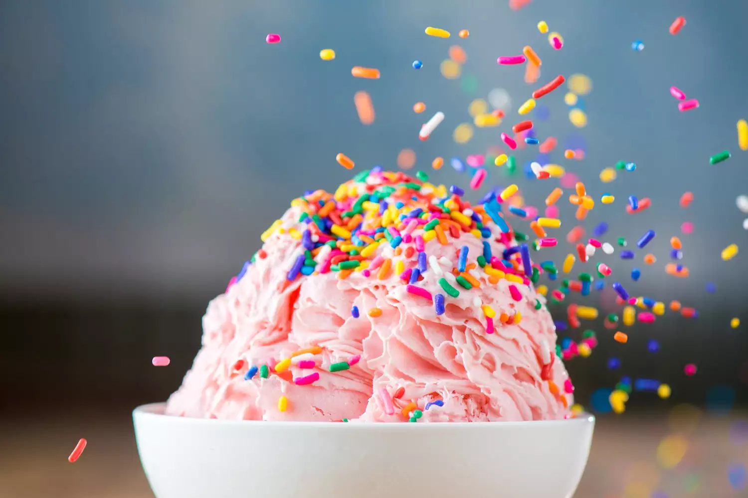 A mound of strawberry shaved snow under a shower of rainbow sprinkles