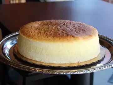 Tall golden-topped soufflé cheesecake on a silver tray