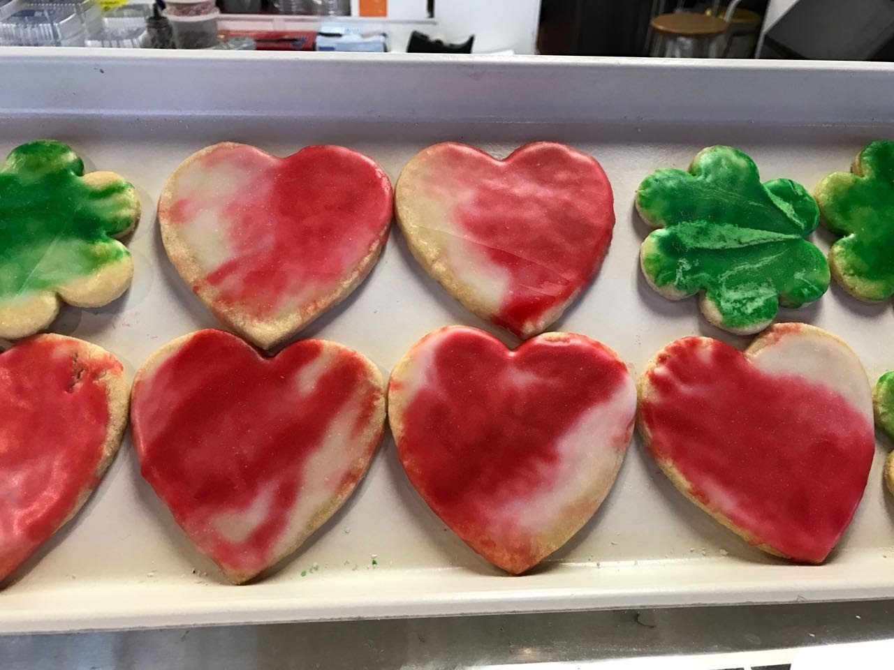 Iced sugar cookies cut into hearts and shamrocks on a tray